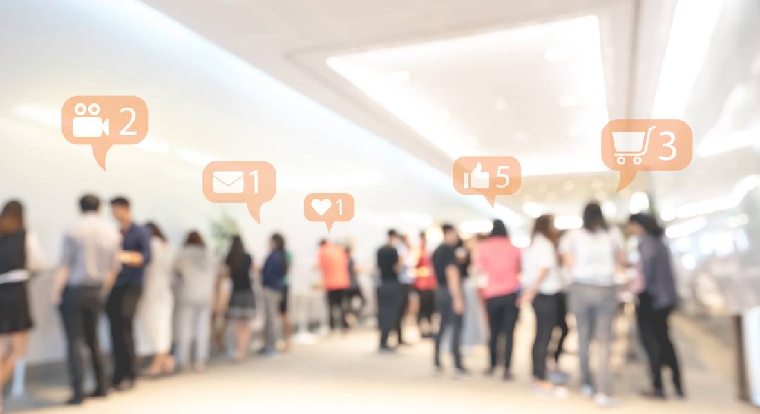 A blurry crowd shot of people attending a live event. Social media reaction bubbles are floating above their heads.