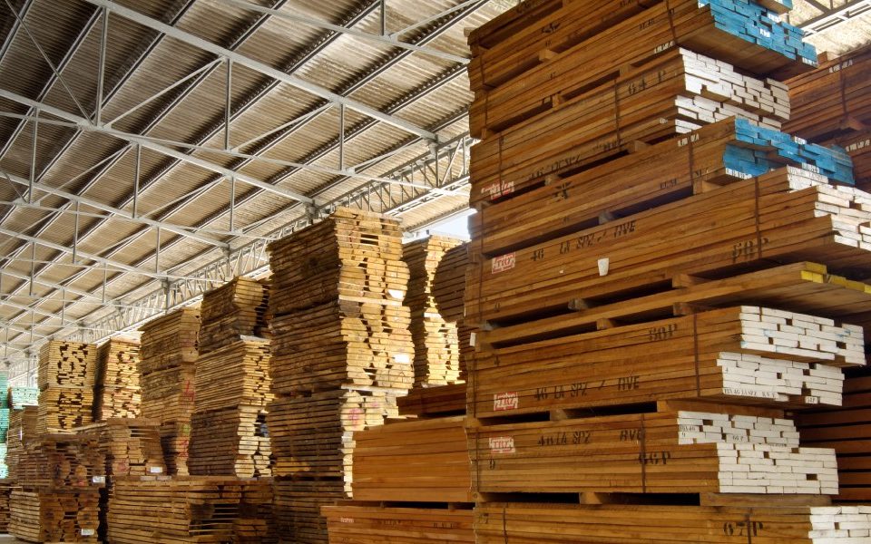 A large warehouse with stacks and stacks of recycled wooden pallets and racking systems. The stacks are bound together.