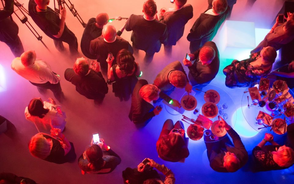 A bird's-eye view of a crowd eating and socializing at a vibrant corporate event in a large, colorful venue.