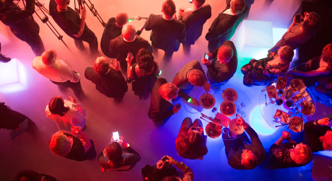 A bird's-eye view of a crowd eating and socializing at a vibrant corporate event in a large, colorful venue.