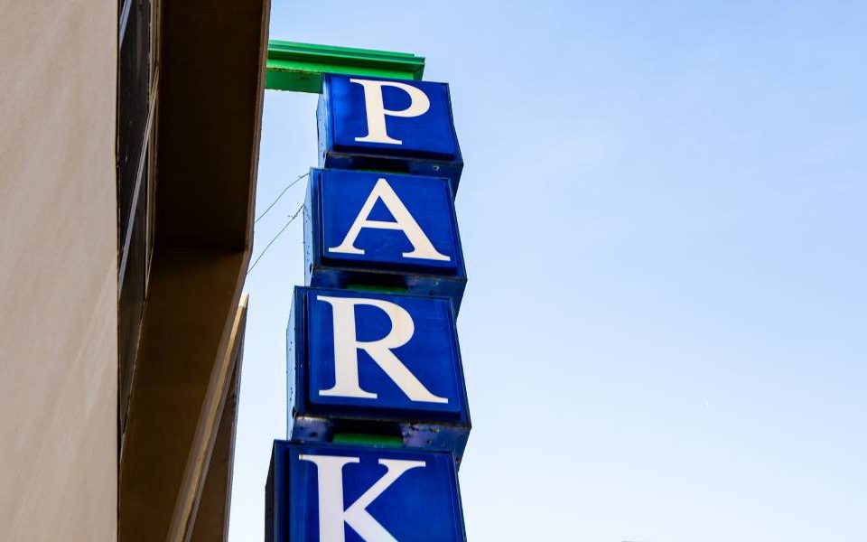 The word "park" spelled vertically in four bright-blue signage cubes attached to the side of a building.